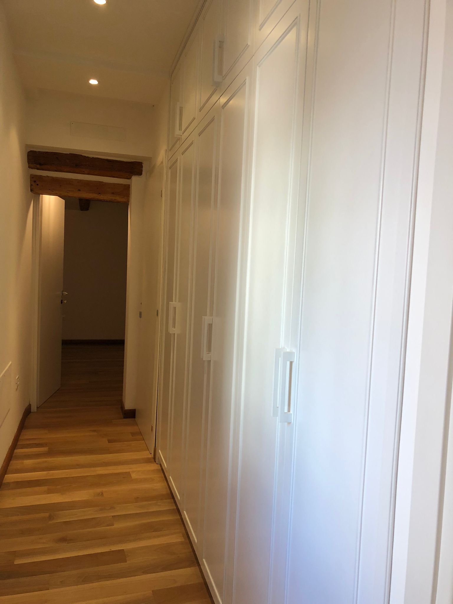 Armadiature su misura a Vicenza in corridoio attrezzato, con ante laccate a tutta altezza e integrazione con cucina su misura