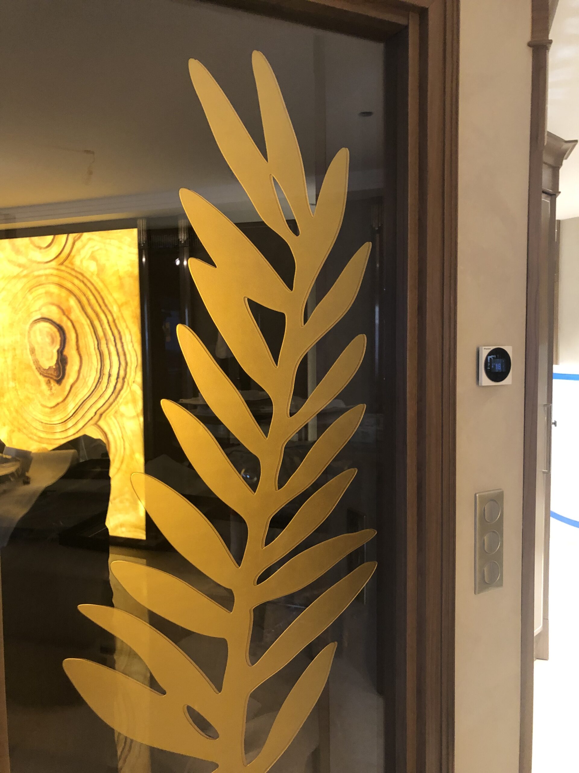 Arredamento su misura a Cannes con pannello decorativo in vetro e motivo vegetale dorato, progetto Martini Verona