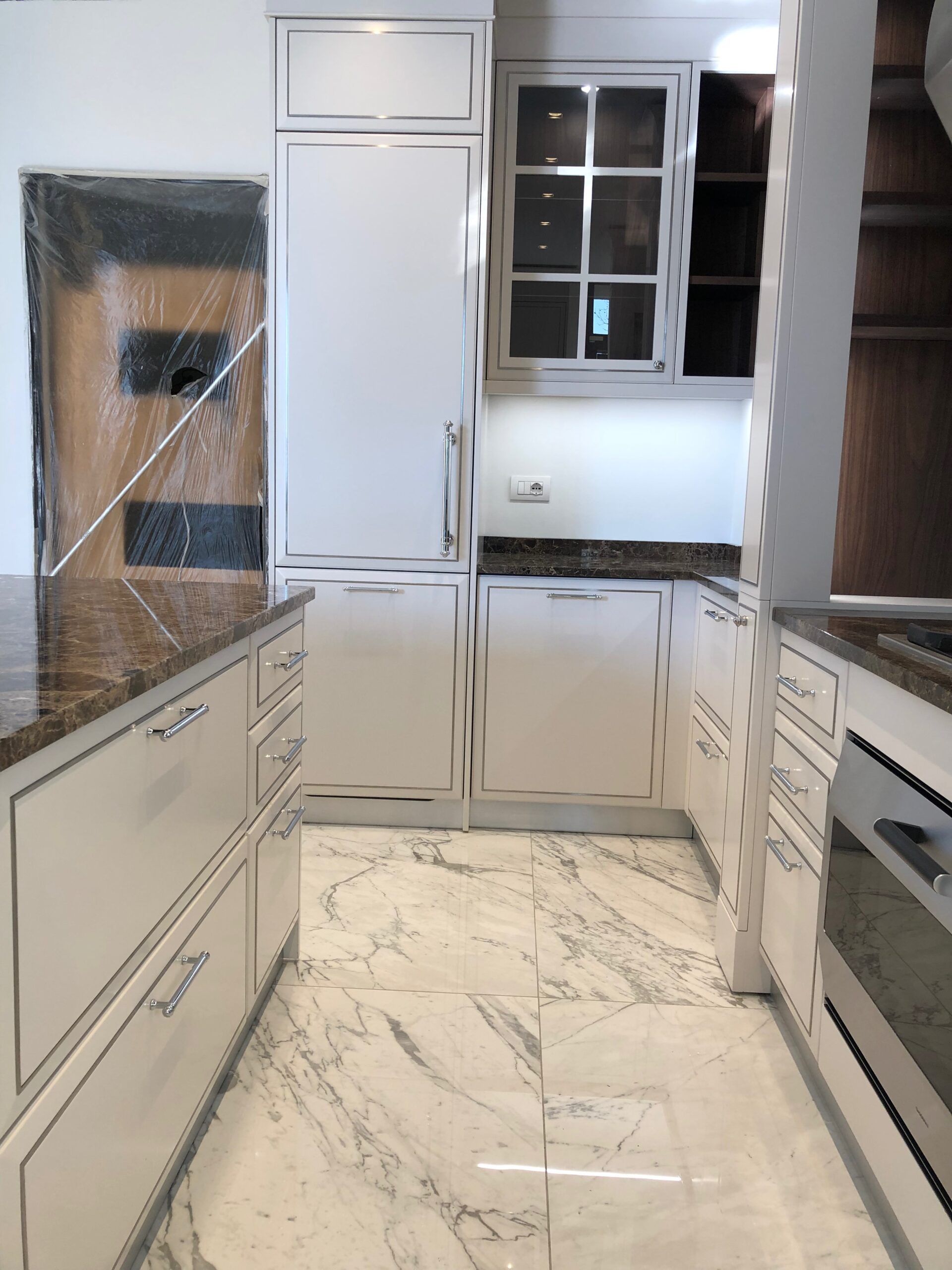 Zona colonne di cucina su misura a Piacenza con forno integrato, basi contenitive e pavimento in marmo, realizzata da Martini Verona