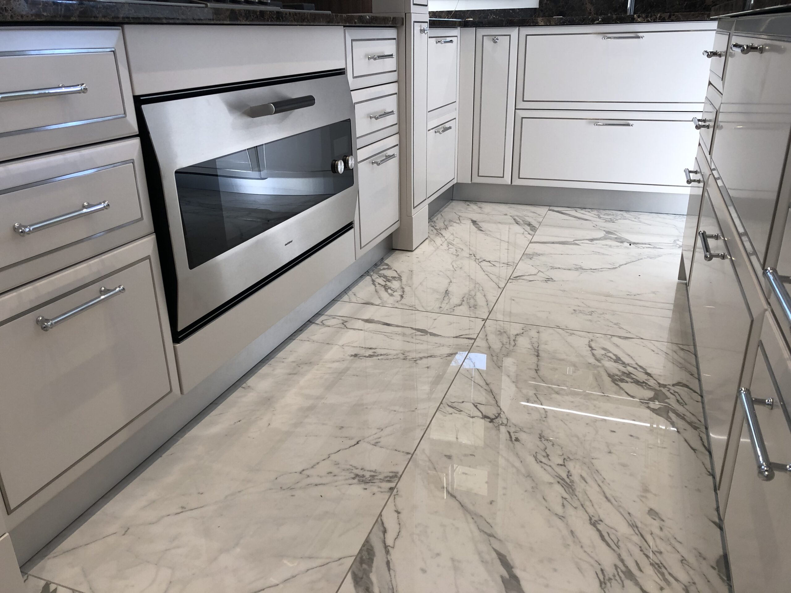 Dettaglio cucina su misura a Piacenza con forno da incasso, basi classiche laccate e pavimento in marmo, realizzata da Martini Verona