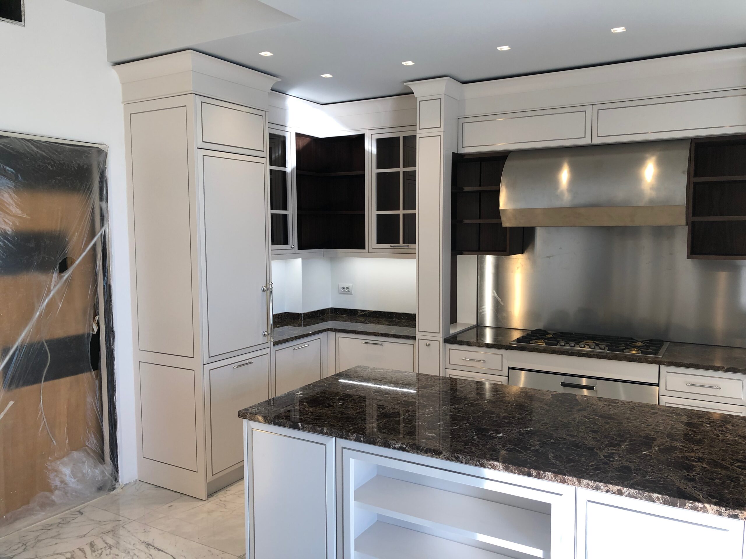 Cucina classica su misura a Piacenza con isola centrale, piano in marmo scuro e zona cottura con cappa integrata, realizzata da Martini Verona