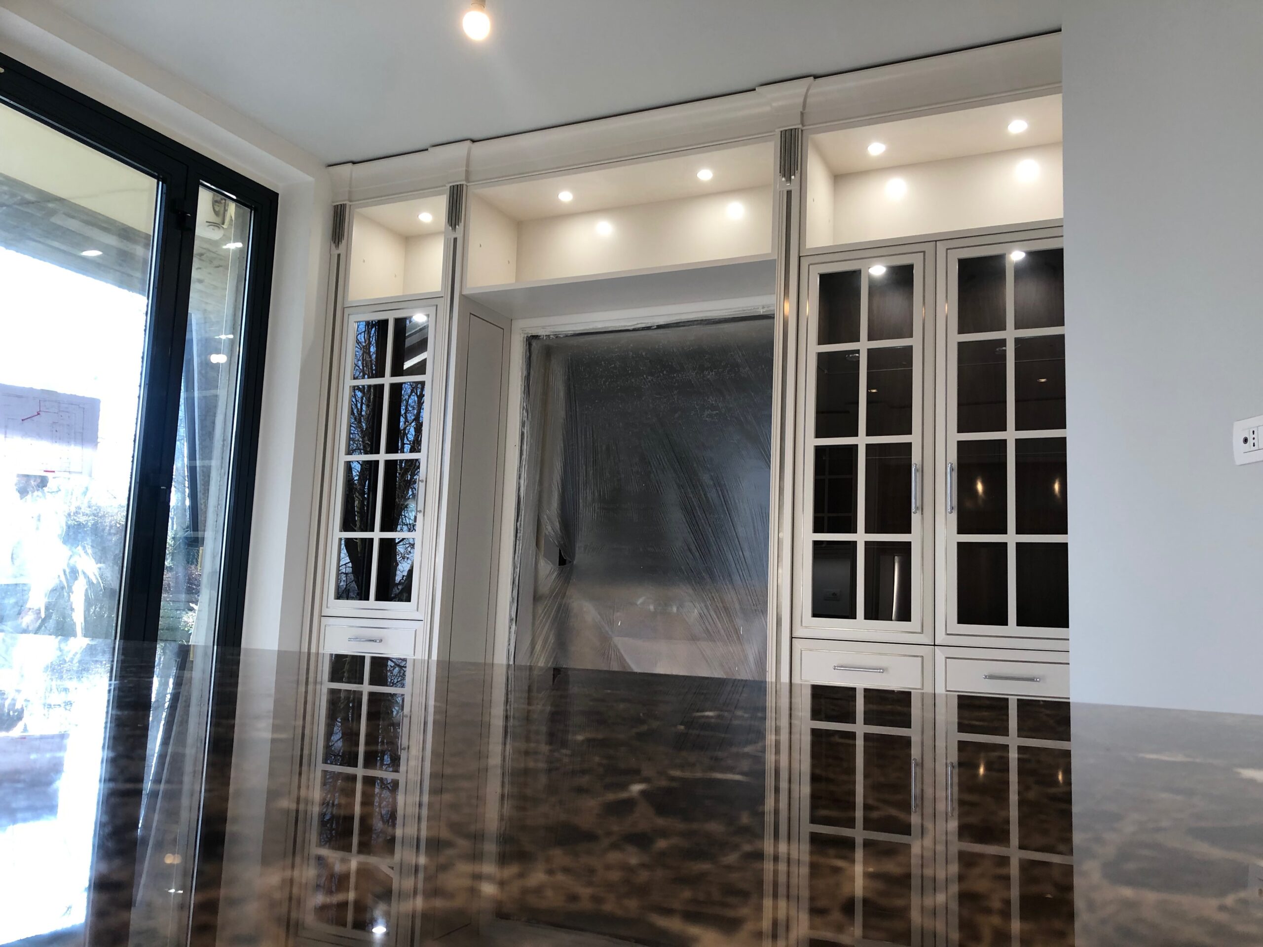 Cucina su misura a Piacenza con parete attrezzata, pensili vetrati e illuminazione integrata, progetto classico Martini Verona