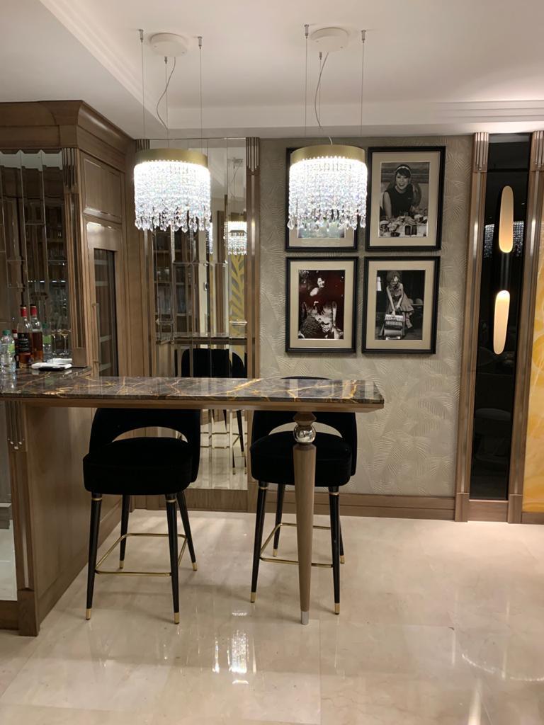 Arredamento su misura a Cannes con bancone bar in marmo, sedute alte e illuminazione a sospensione, progetto Martini Verona