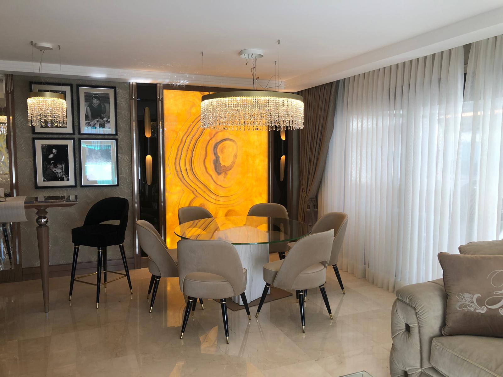 Arredamento su misura a Cannes con zona pranzo, tavolo rotondo in vetro e parete decorativa retroilluminata, realizzato da Martini Verona