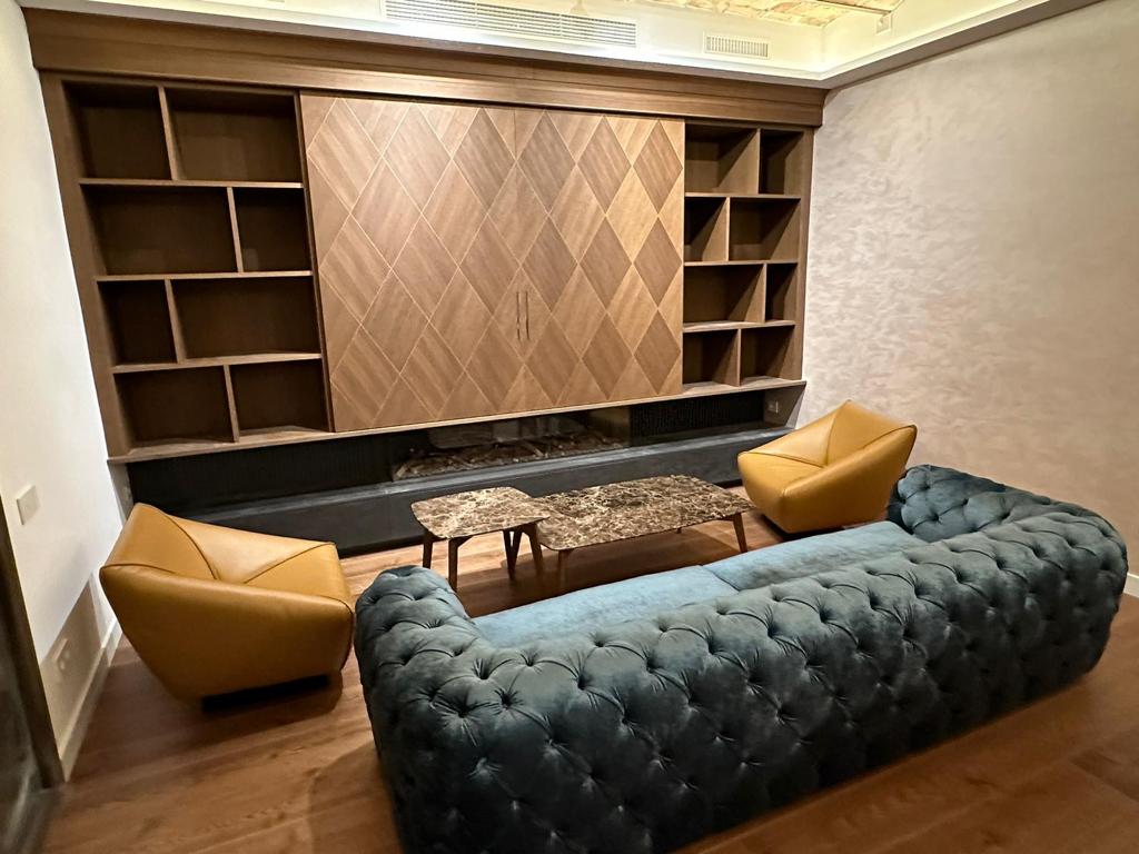Arredo living su misura a Barcellona con boiserie e libreria in legno realizzato da Martini Verona