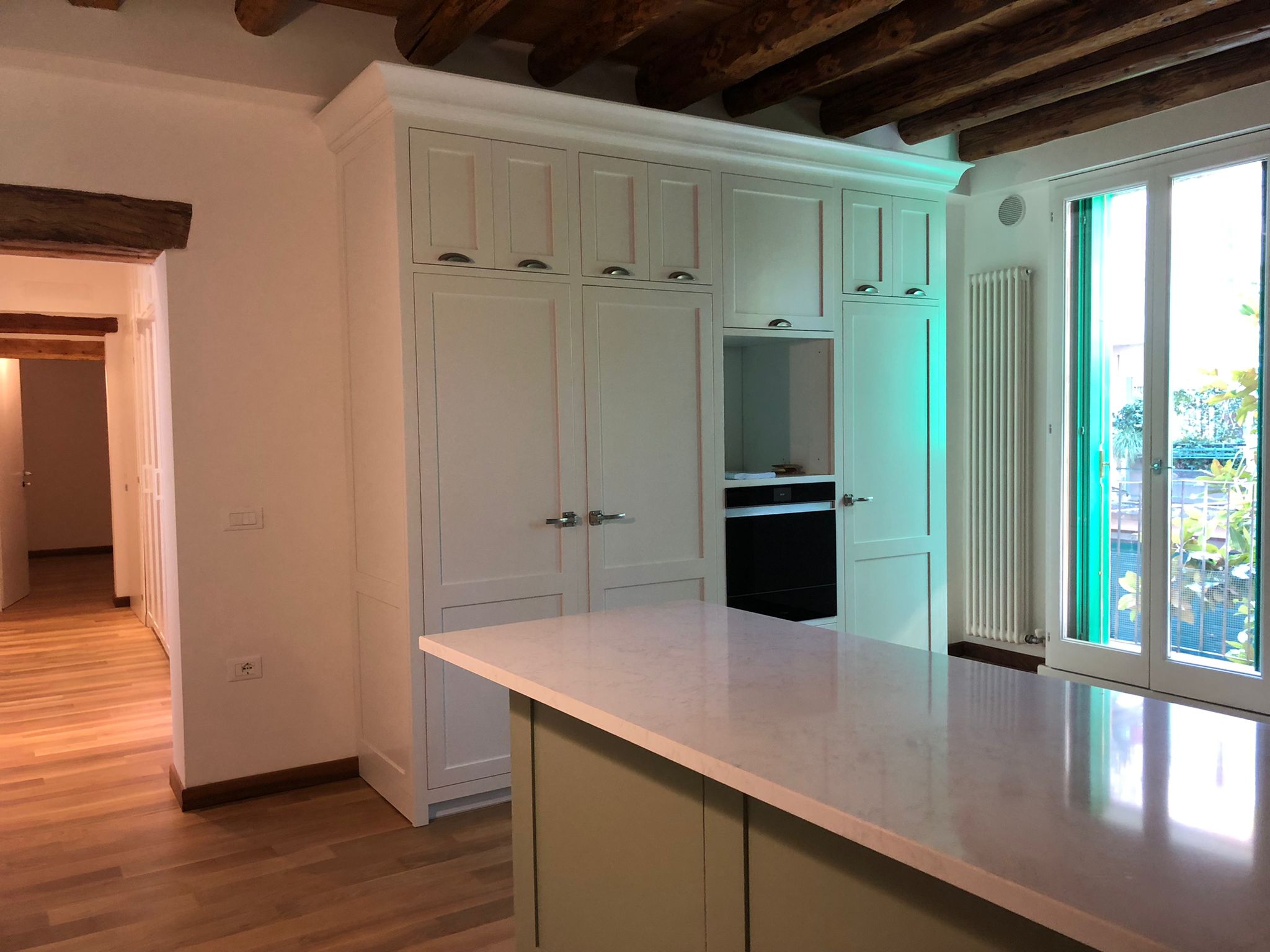 Cucina su misura a Vicenza con zona colonne e isola centrale, ante classiche laccate, forno integrato e travi a vista, realizzata da Martini Verona