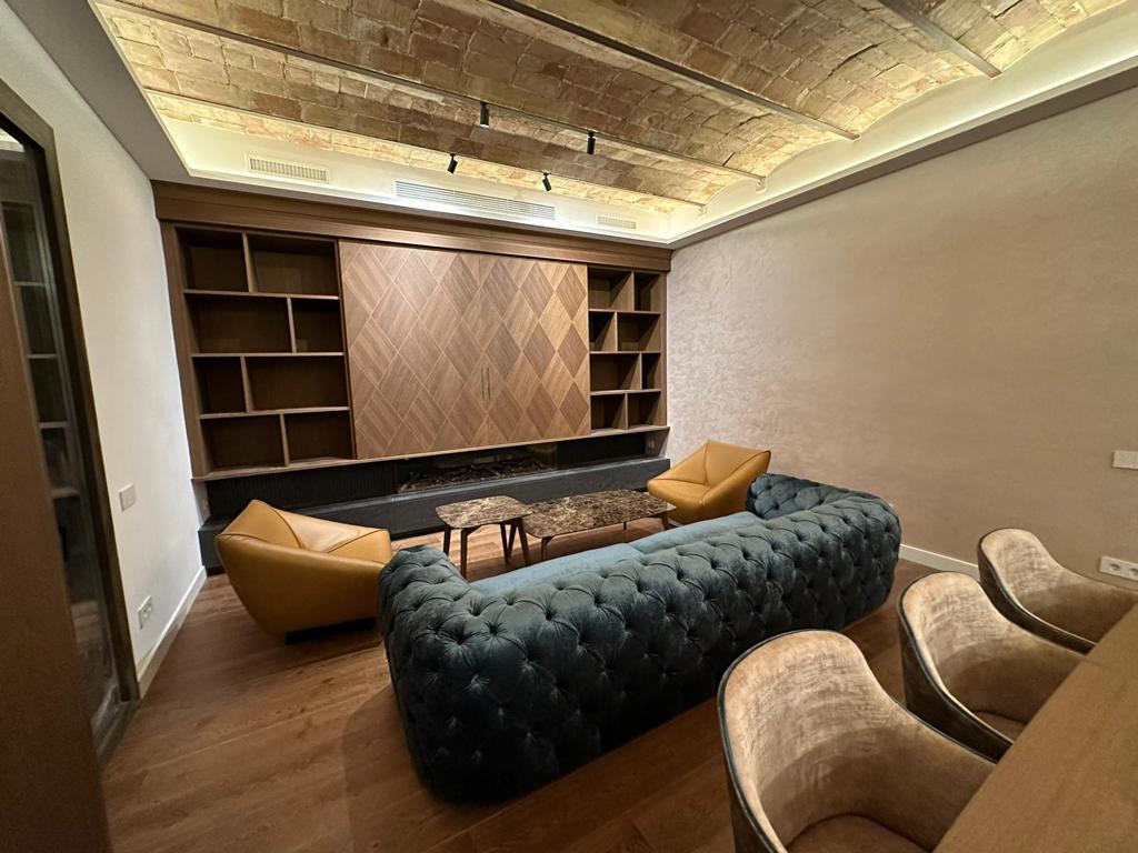 Cucina e arredamento su misura realizzati da Martini Verona a Barcellona con boiserie in legno, libreria integrata e area living coordinata