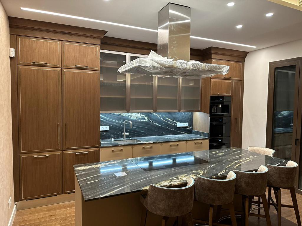 Cucina su misura realizzata da Martini Verona a Barcellona con isola centrale in marmo, colonne in legno e cappa integrata